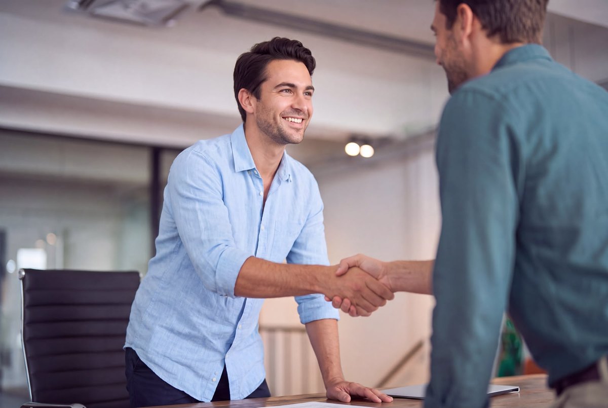 A recruiter shaking hands with a new hire in an office