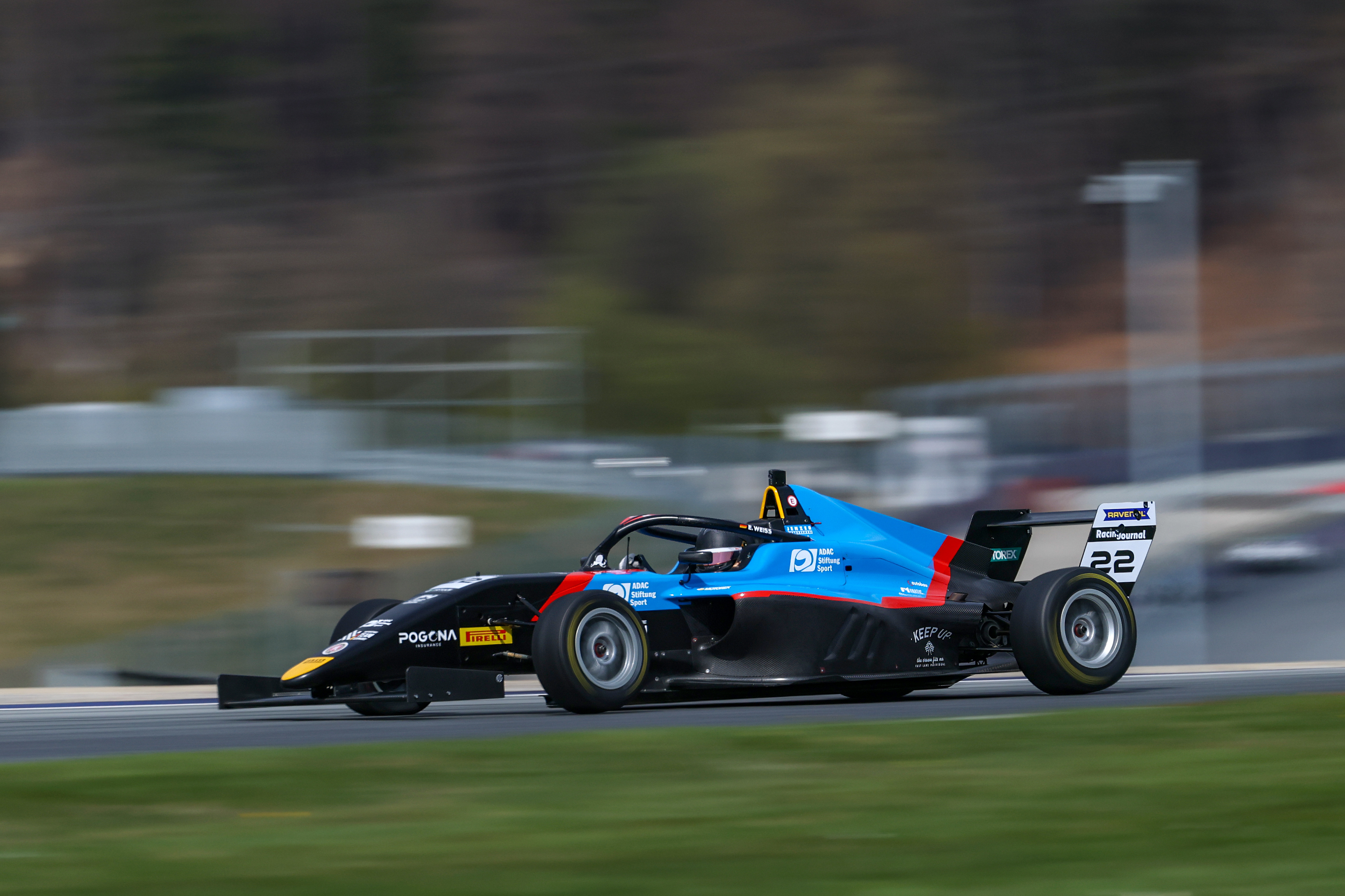 Elia Weiss with number 22 speeding on a racetrack with blurred background.