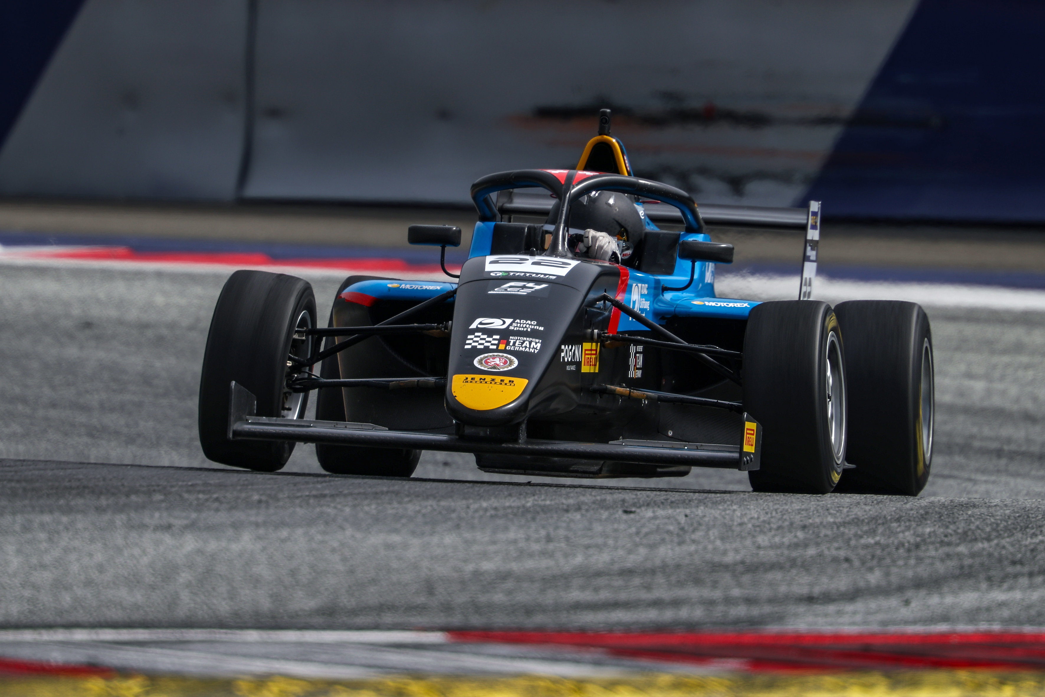 Black and blue formula race car with Elia Weiss on a racetrack.