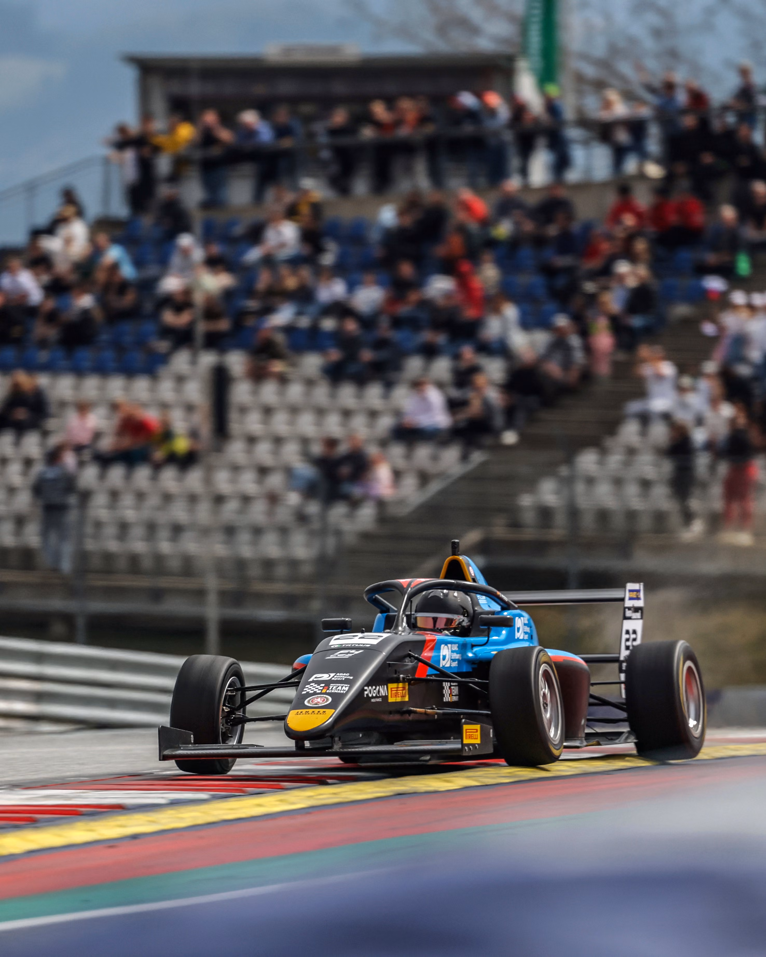 Elia Weiss speeding on a racetrack with spectators in the background.