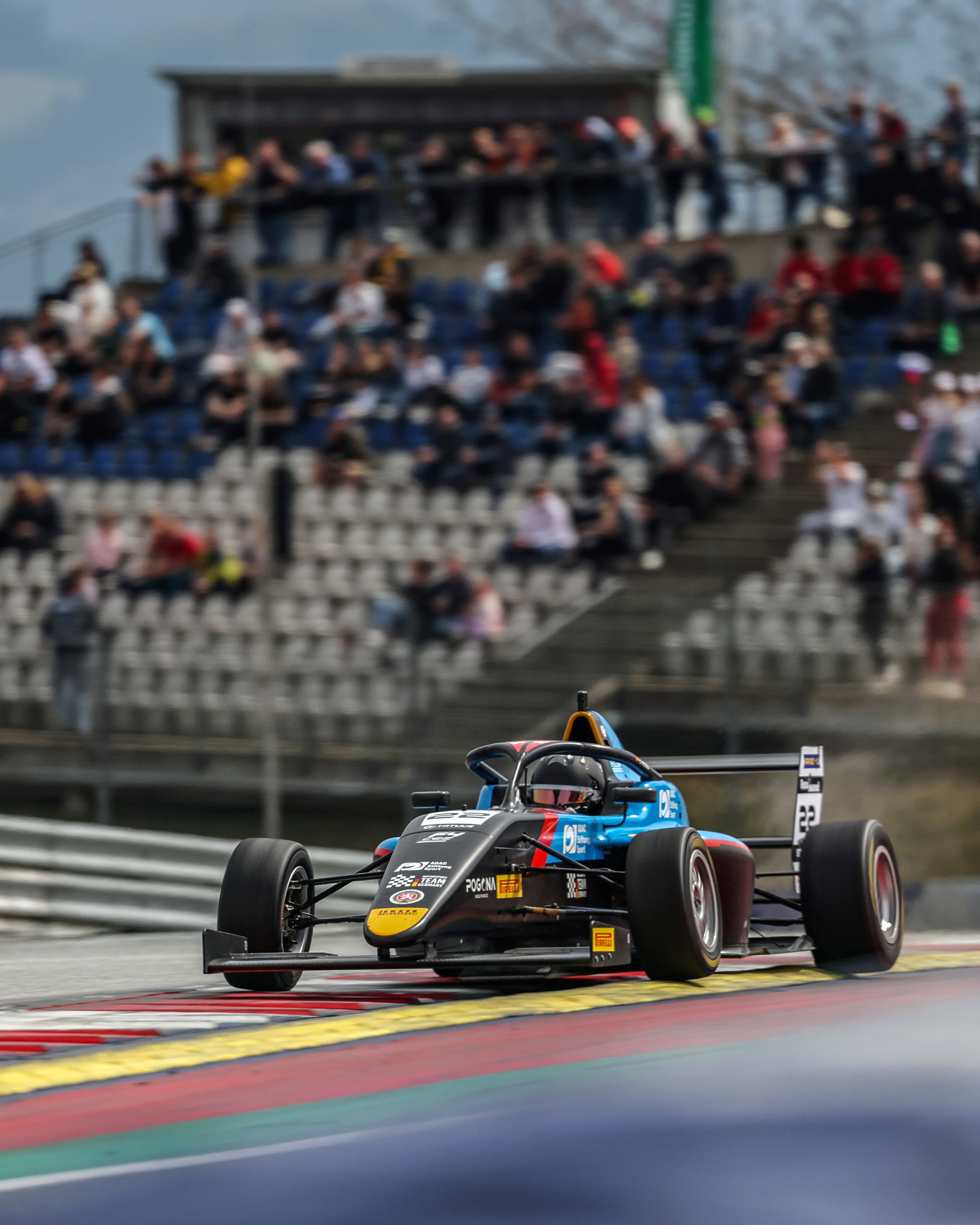 Elia Weiss speeding on a racetrack with spectators in the background.