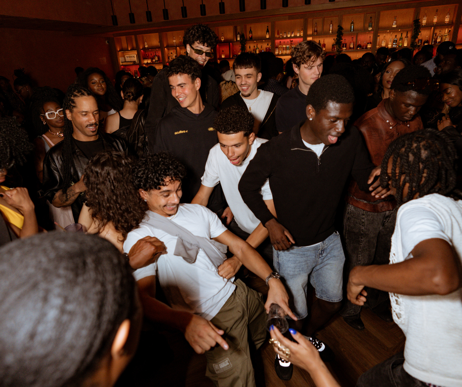 Tight crowd of young people packed together at a dimly lit indoor party