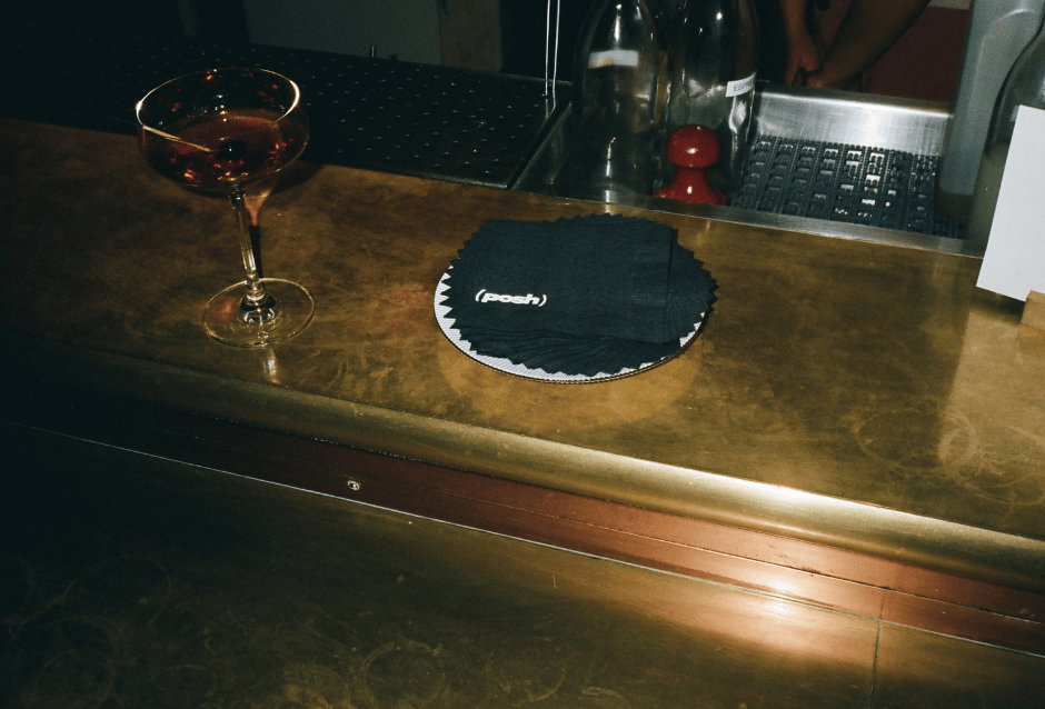 Cocktail glass and round coaster on a polished wood-and-brass bar counter