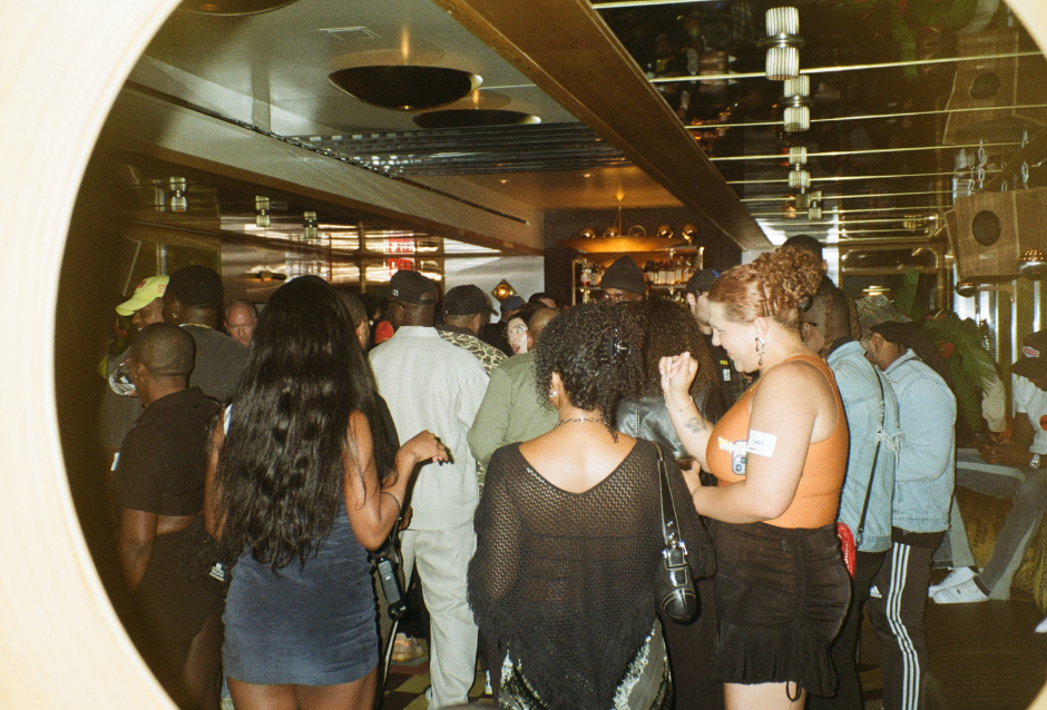 Partygoers mingling and drinking along a long bar in a warmly lit venue