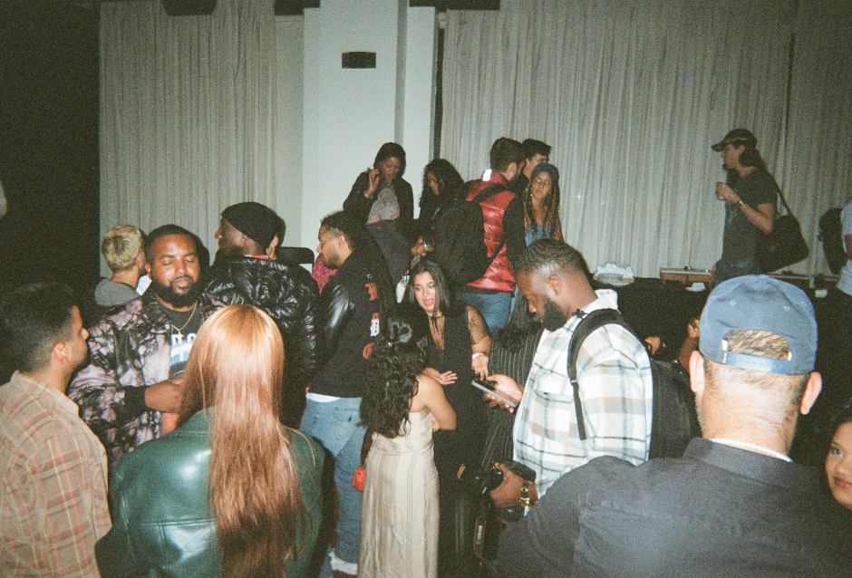 Crowd of people socializing and drinking at a dimly lit indoor party