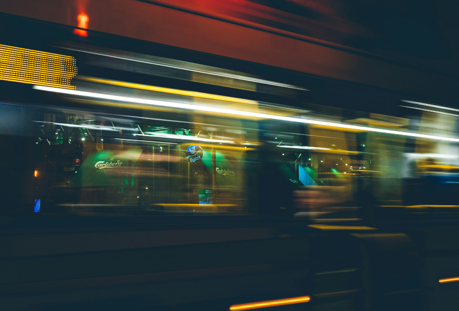 Motion-blurred night scene of a passing lit train or transit car
