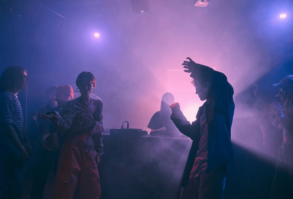 Crowd dancing under purple haze and lights at a nightclub party