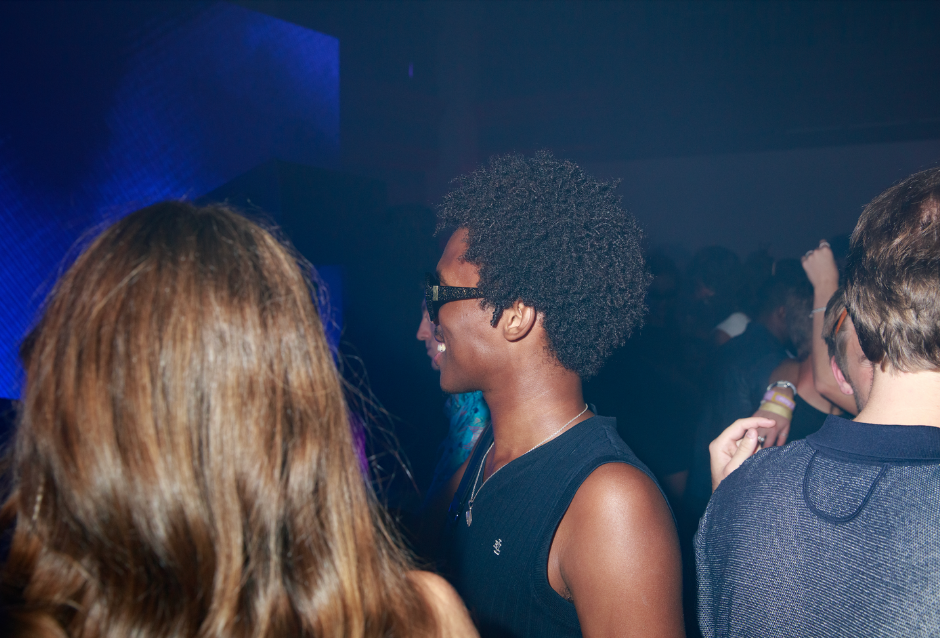 Young people dancing close together in dim blue nightclub lighting