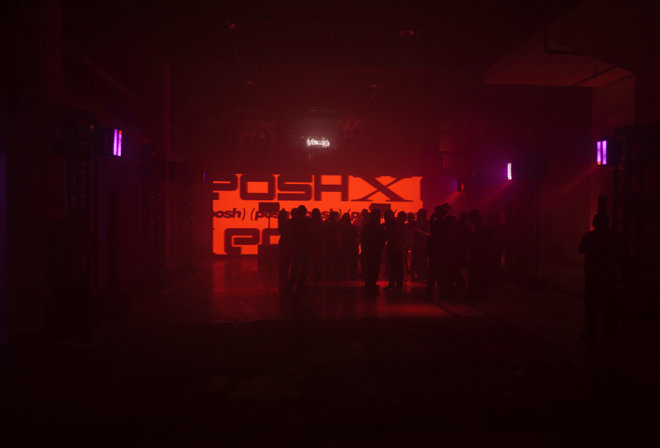 Silhouetted crowd before a glowing red 'Posh' logo wall in a dark venue