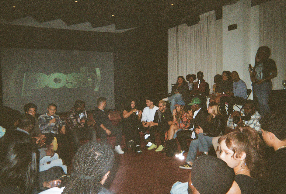 Crowd seated on the floor watching a presentation in a dim room