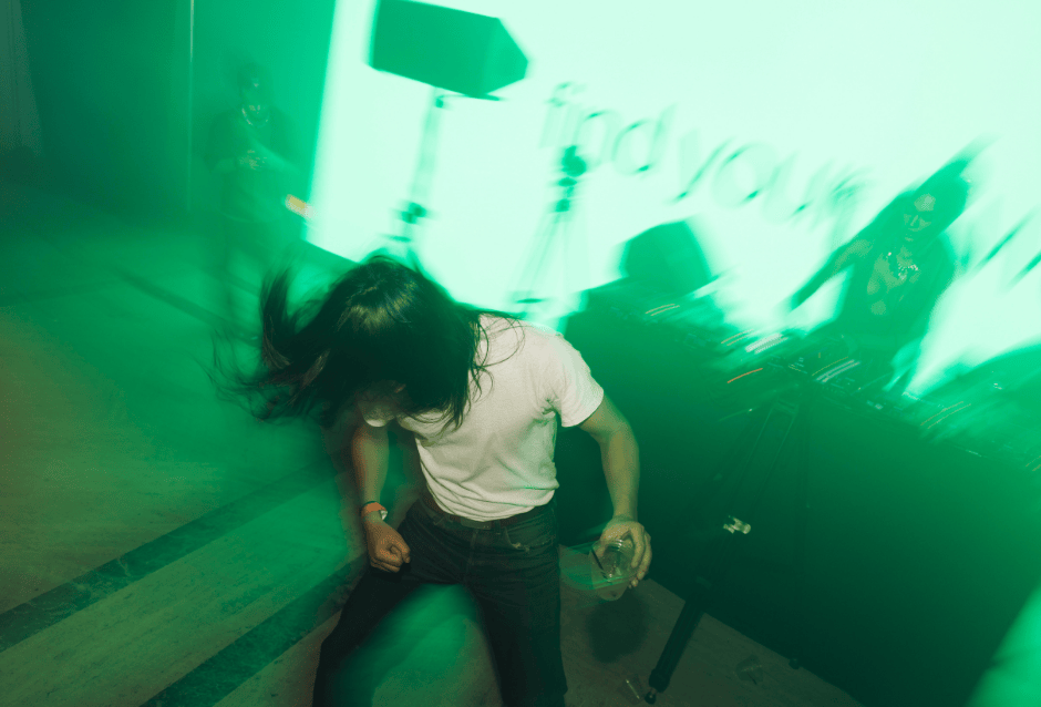 Person dancing energetically under hazy green light, motion-blurred