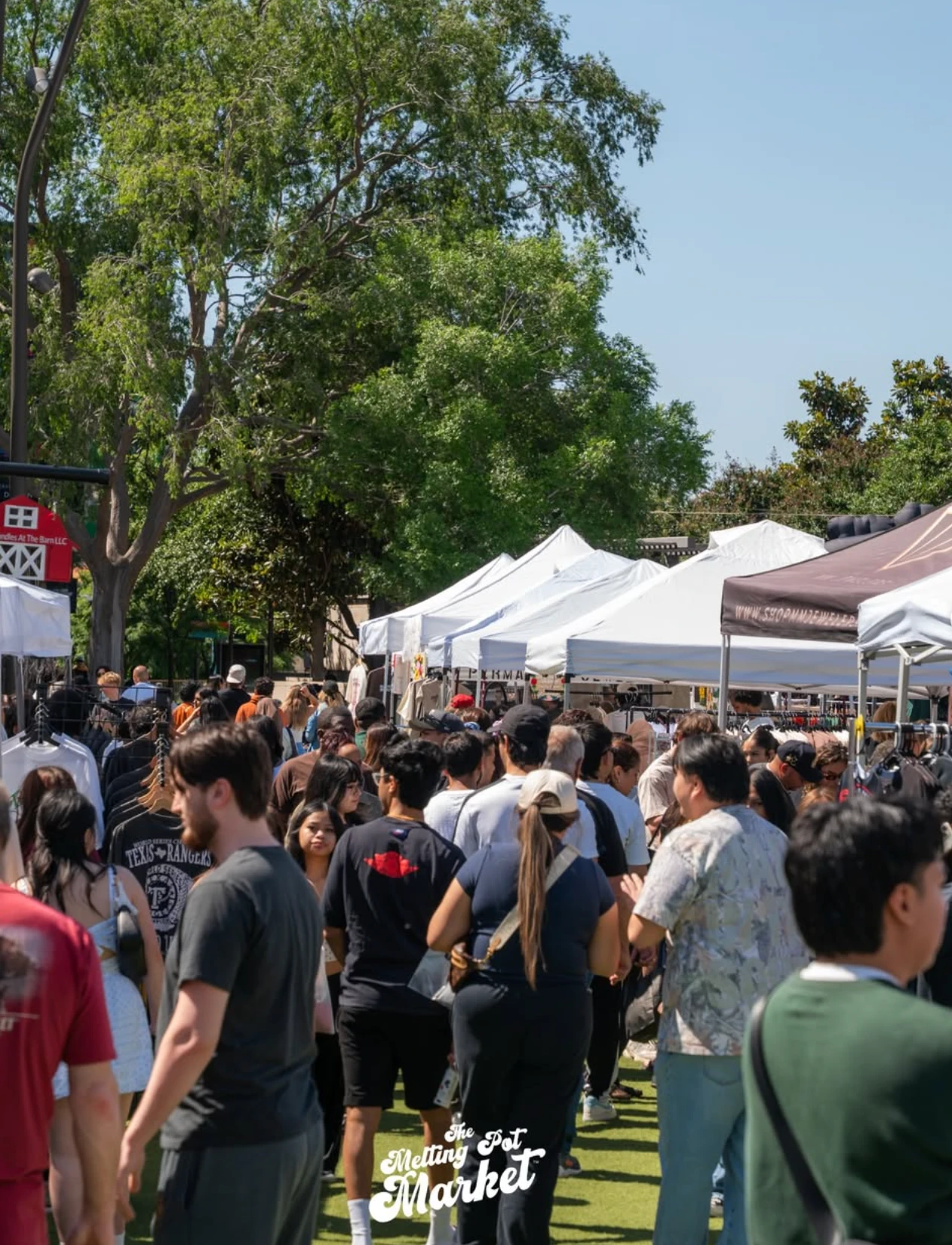 Shoppers walking rows of vendor tents at The Melting Pot Market
