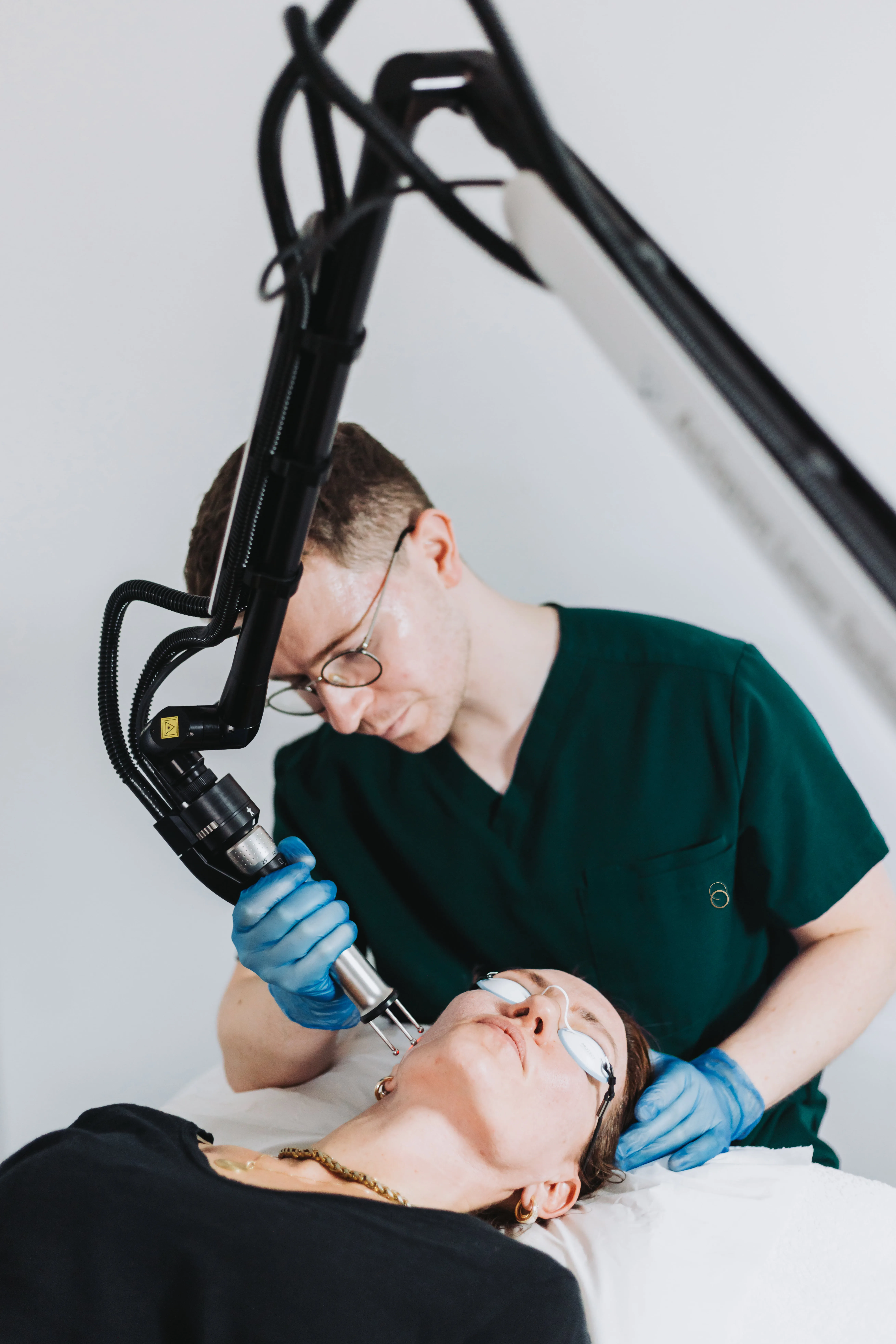 Modern office reception with illuminated Aion Labs sign on black marble wall, green velvet chairs, and tall plants.