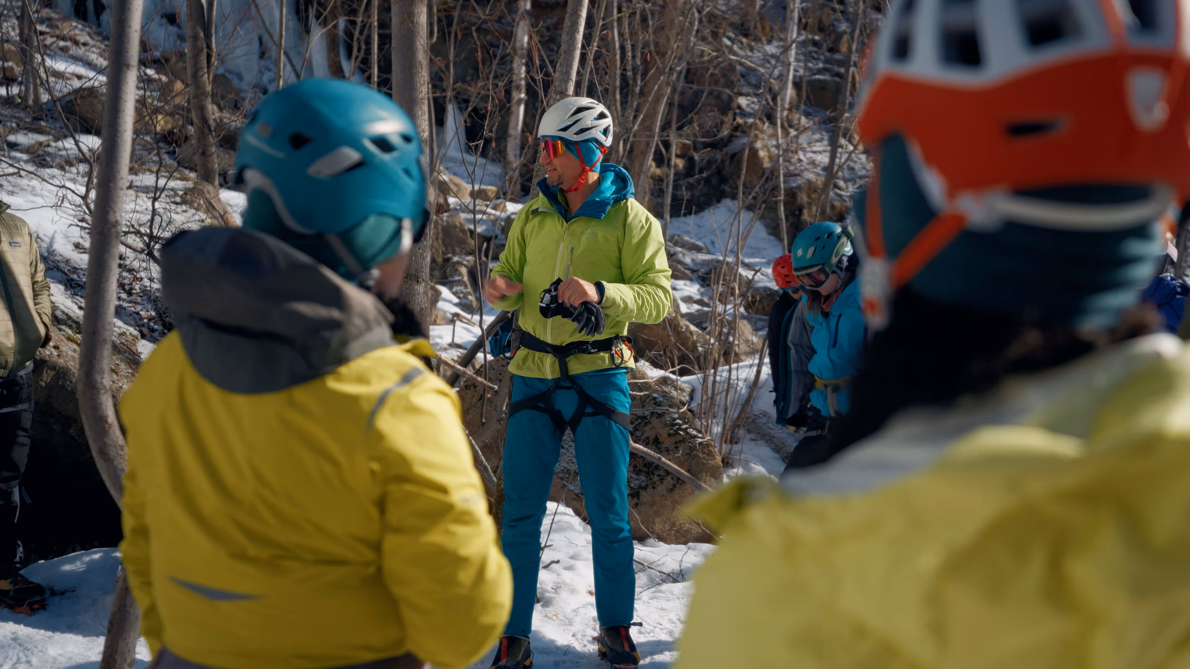 Man equipped to ice climb speaking to a group on the Escala NICW project by Colt Bradley