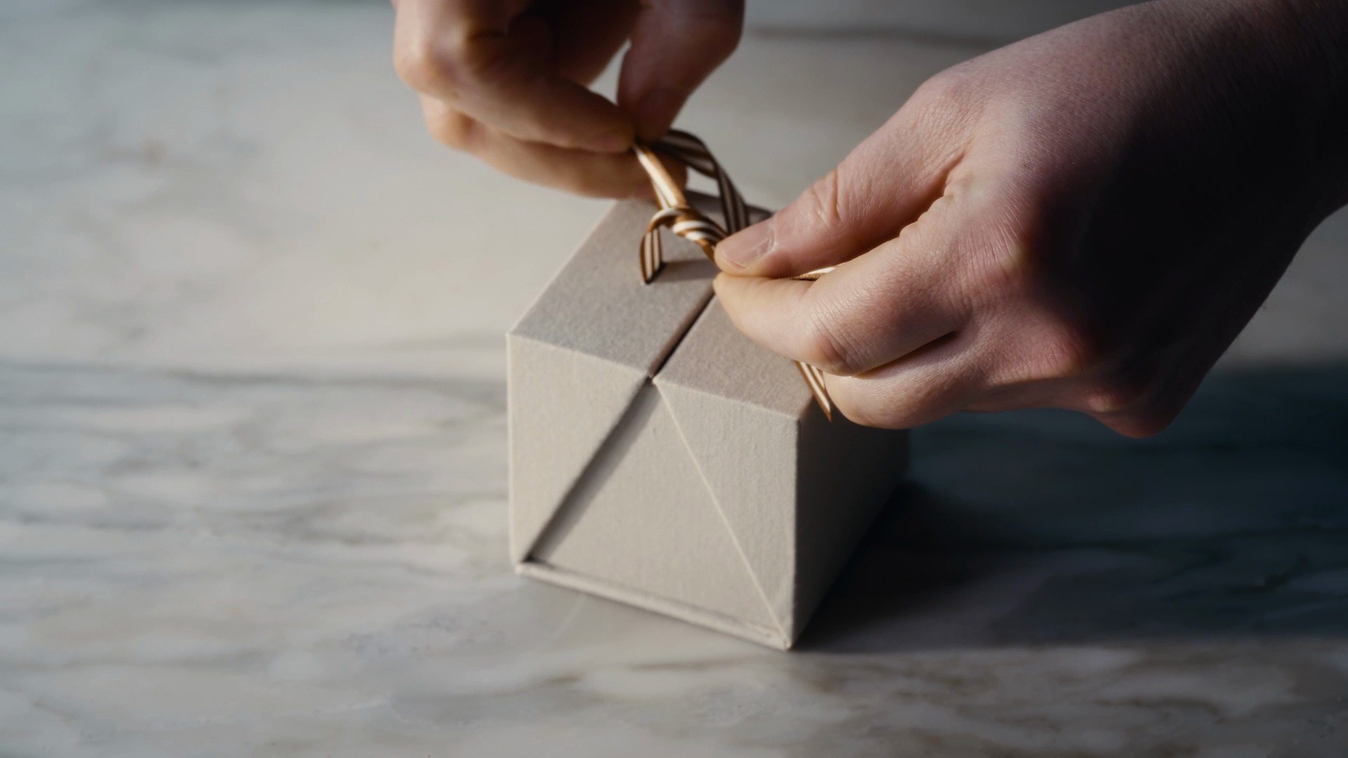 Hands tying the ribbon and tag on the Signature Easter Egg box