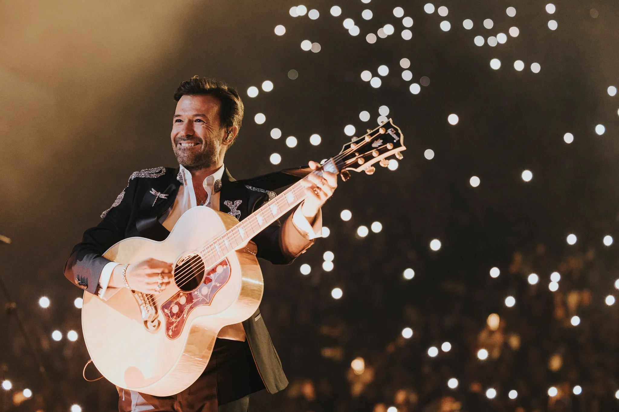 Yalın gitar çalıyor ve gülümsüyor