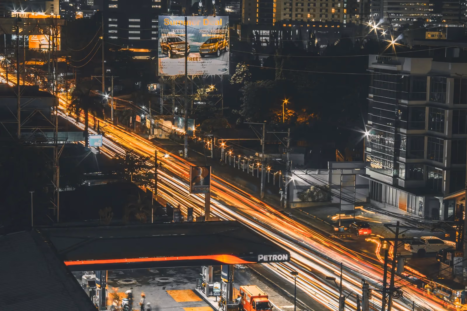 Illuminated highway billboard above heavy night traffic in a city centre