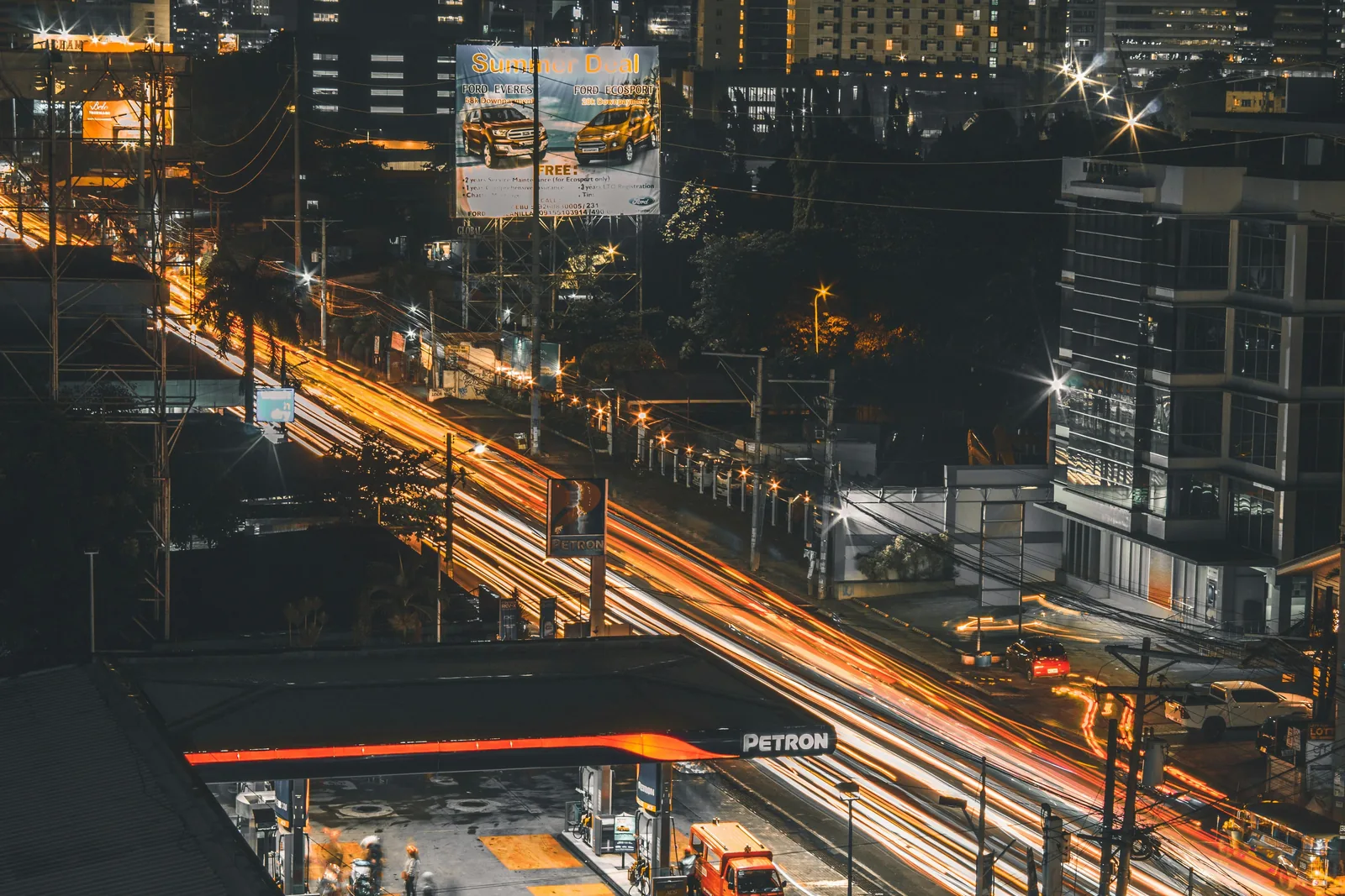 Illuminated highway billboard above heavy night traffic in a city centre
