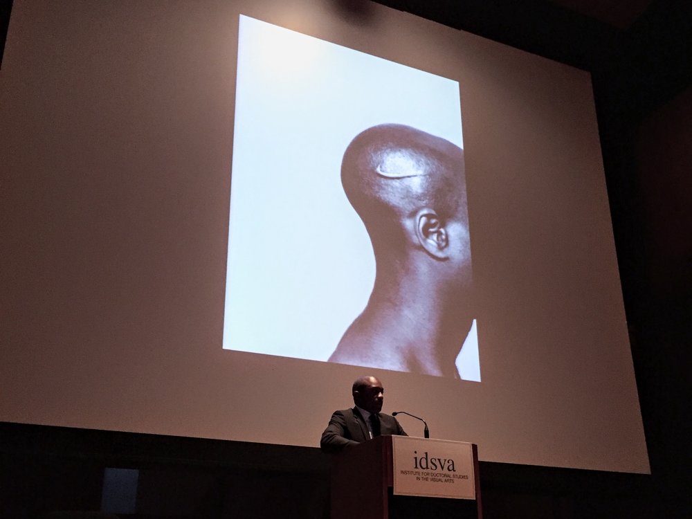 Hank Willis Thomas speaking at the 2017 IDSVA Commencement in NYC with his work  Branded Head (2003) displayed. Photo by Simonetta Moro
