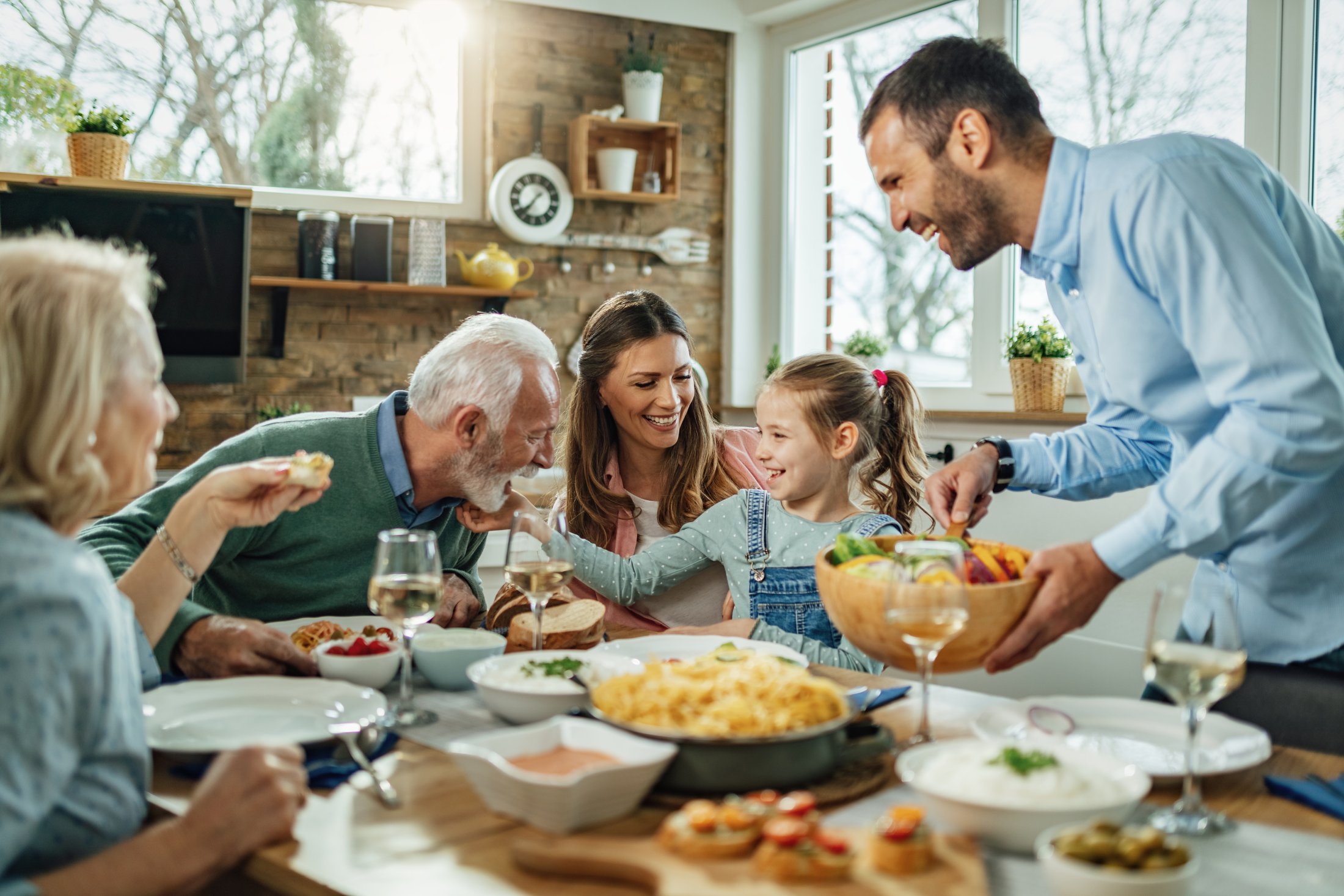 A family of three together with their elderly parents are having fun at a meal