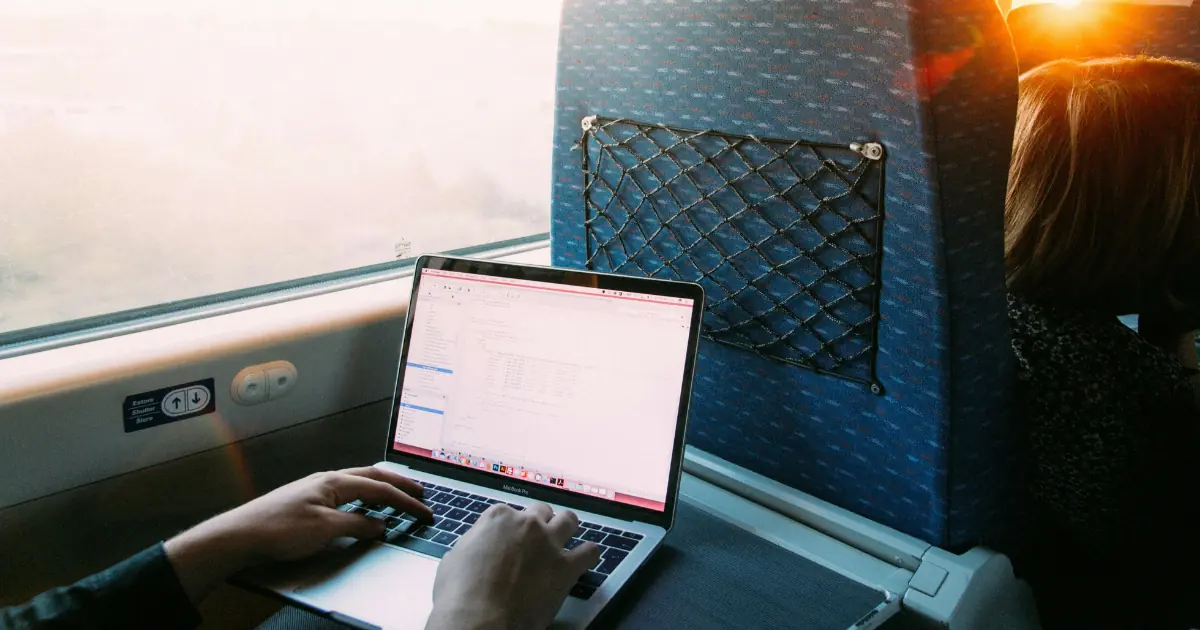 Passenger working on a train with onboard Wi-Fi — train wifi quality varies by country