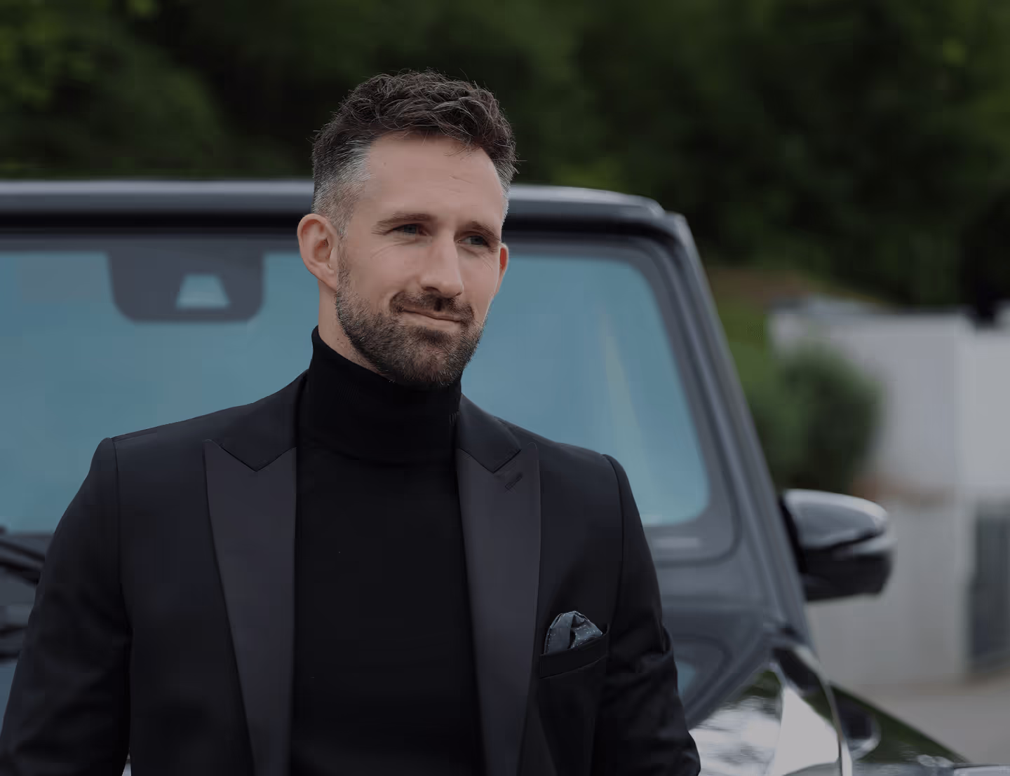 Mann mit Anzug vor Auto