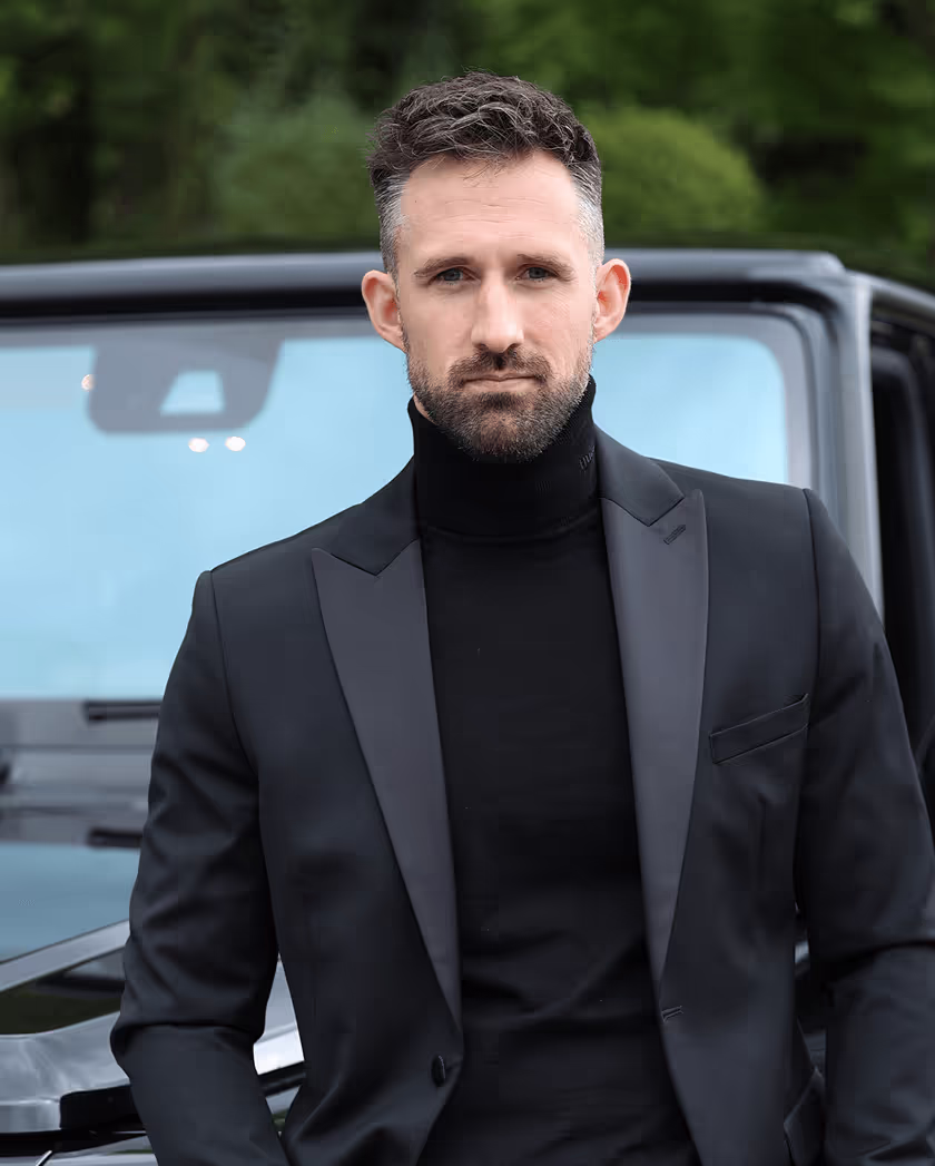 Mann mit Anzug vor Auto