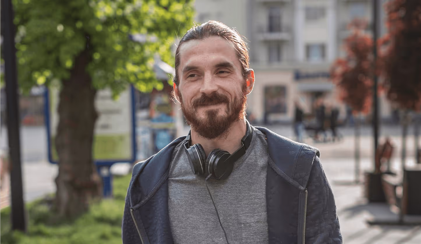 Lächelnder Mann mit Kopfhörern und sportlich gekleidet unterwegs