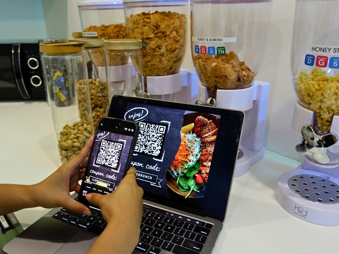 A restaurant customer using a smartphone and laptop to interact with digital menu and ordering tools