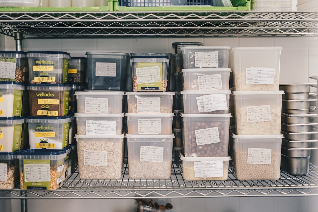 Labeled food containers neatly organized on stainless kitchen shelves in a restaurant storeroom