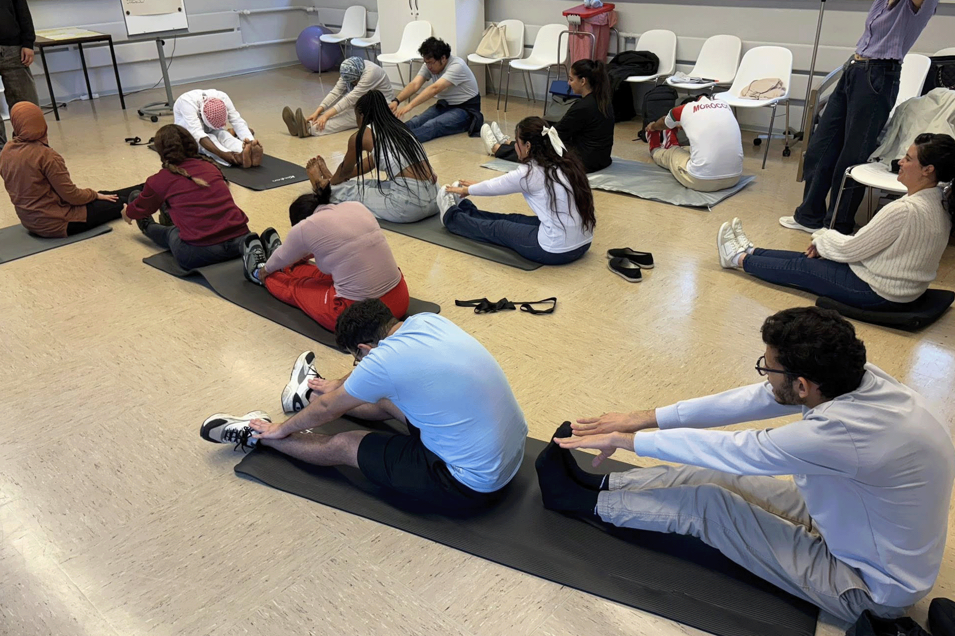 Die Azubis sitzen auf Yogamatten und dehnen sich