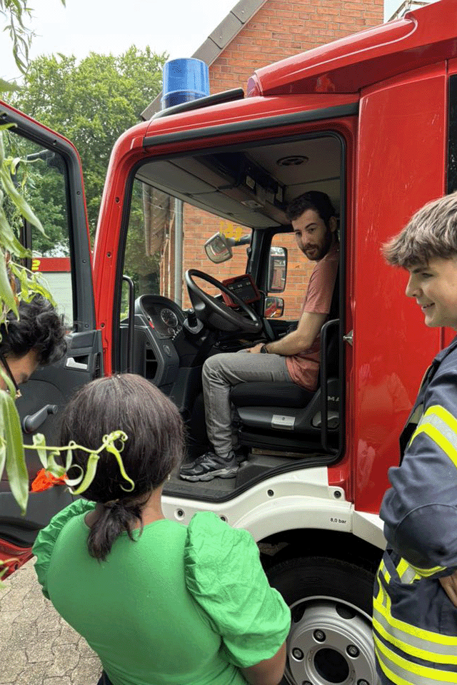 Auszubildene sitzen auf dem Fahrersitz des Feuerwehrautos.
