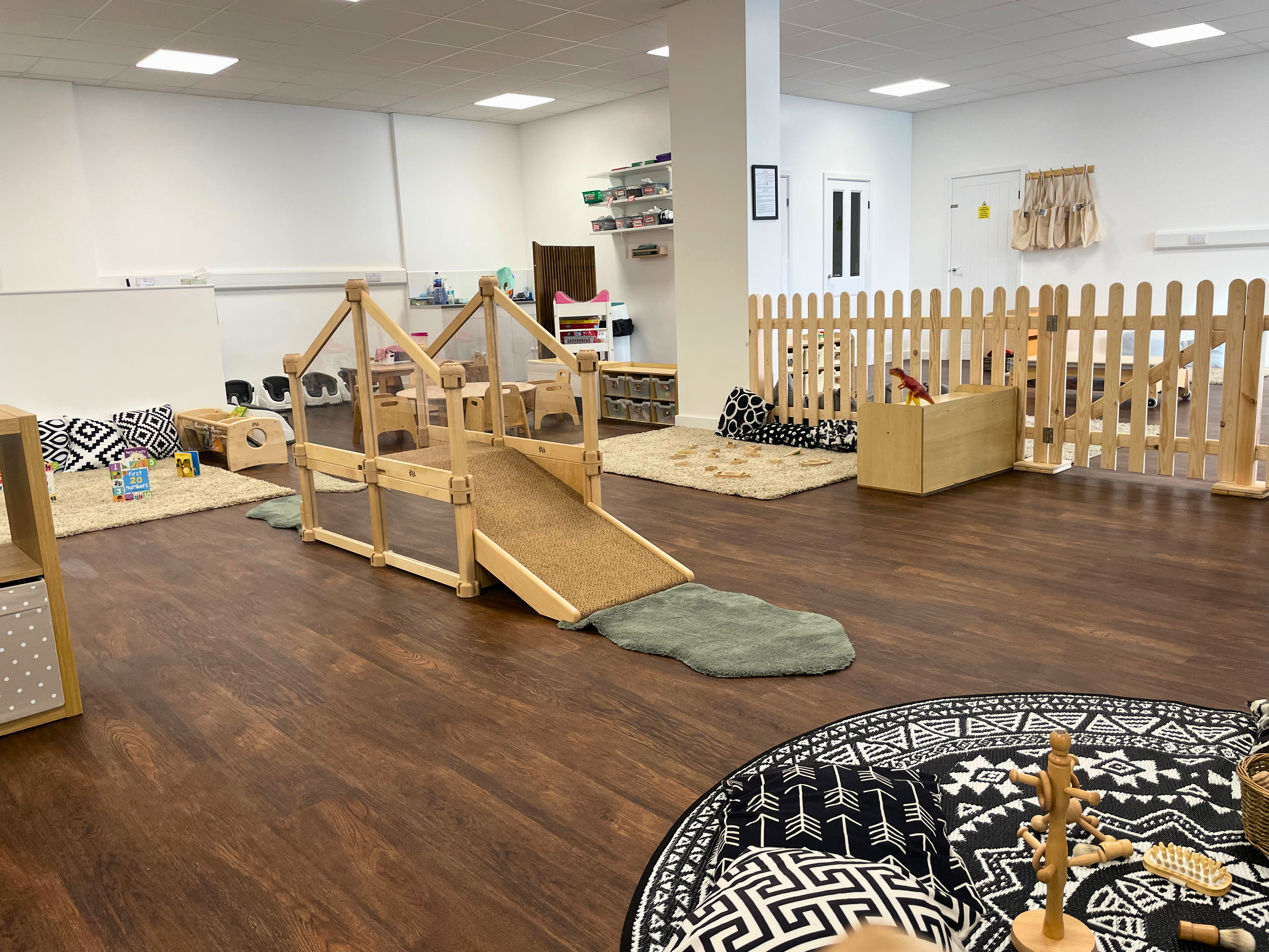 Spacious early years nursery room with wooden climbing bridge, soft play rugs, learning zones and natural resources, supporting physical development and child‑led play in a childcare setting, nursery walthamstow, day nurseries in walthamstow, day nursery