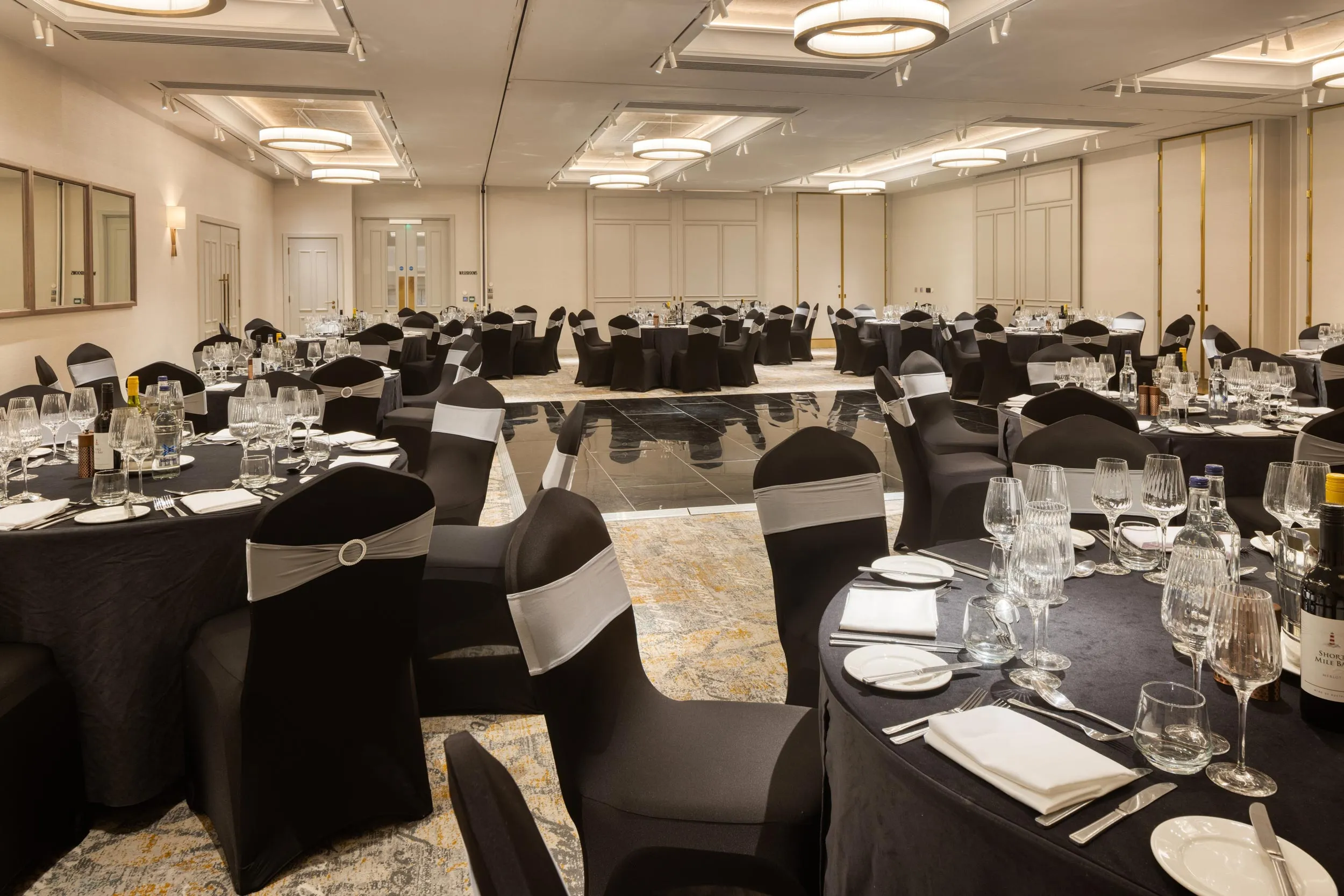 A black and white photo of a large room with a dining table and chairs.
