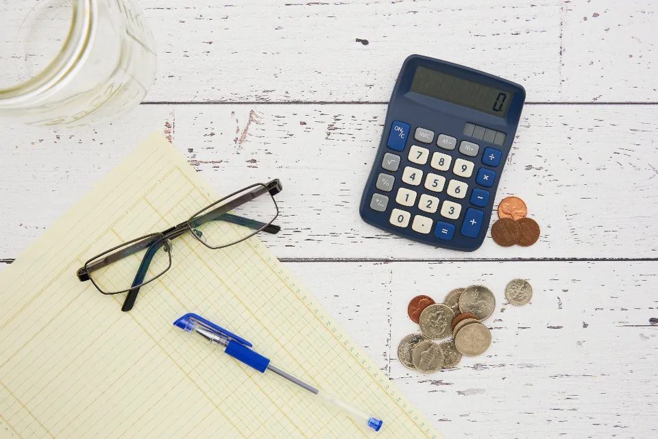 Calculator, ledger paper and coins used to work out how much dropshippers make per month
