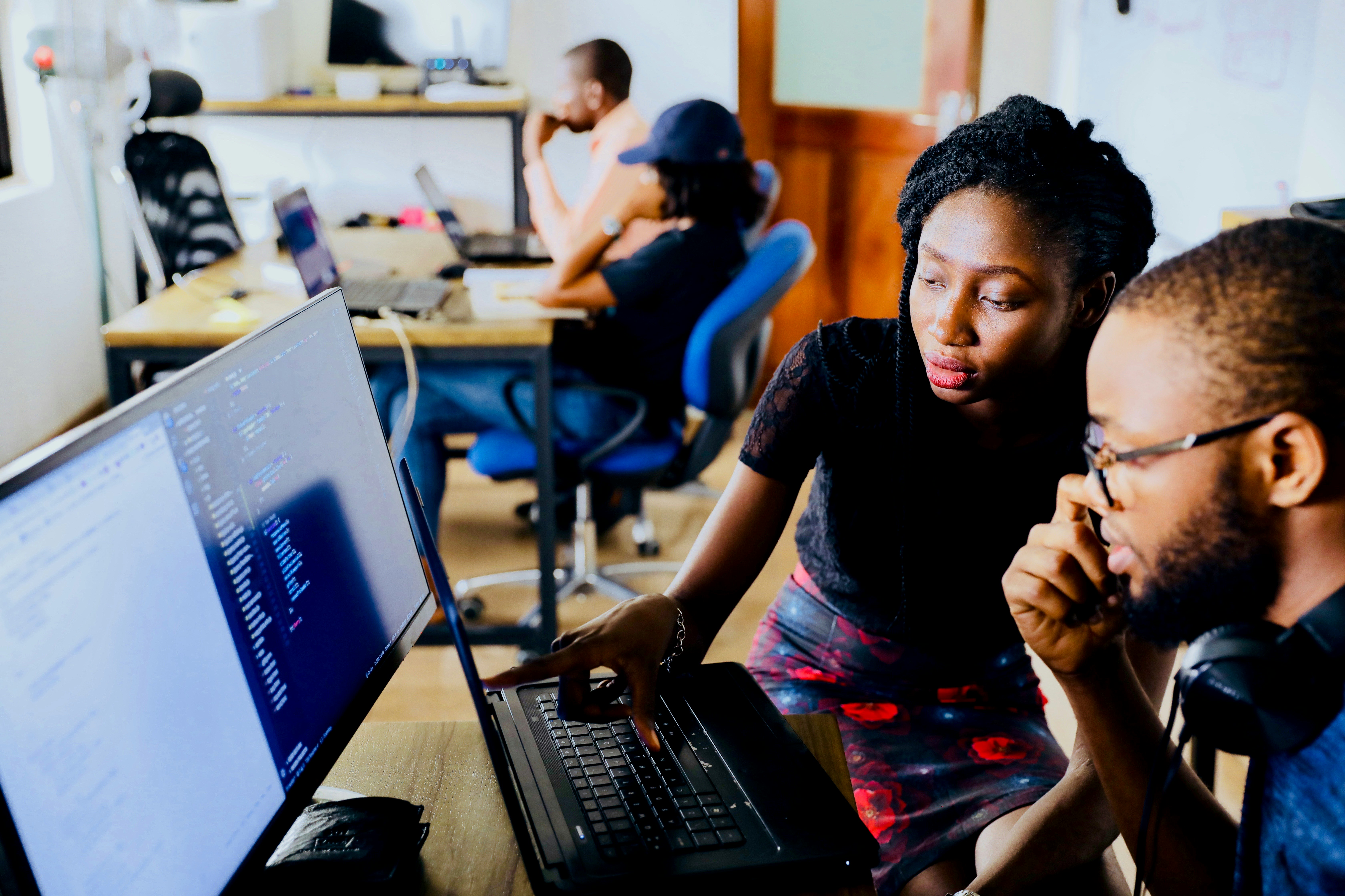 Two people are intently focused on a computer screen, concentrating on what they are seeing