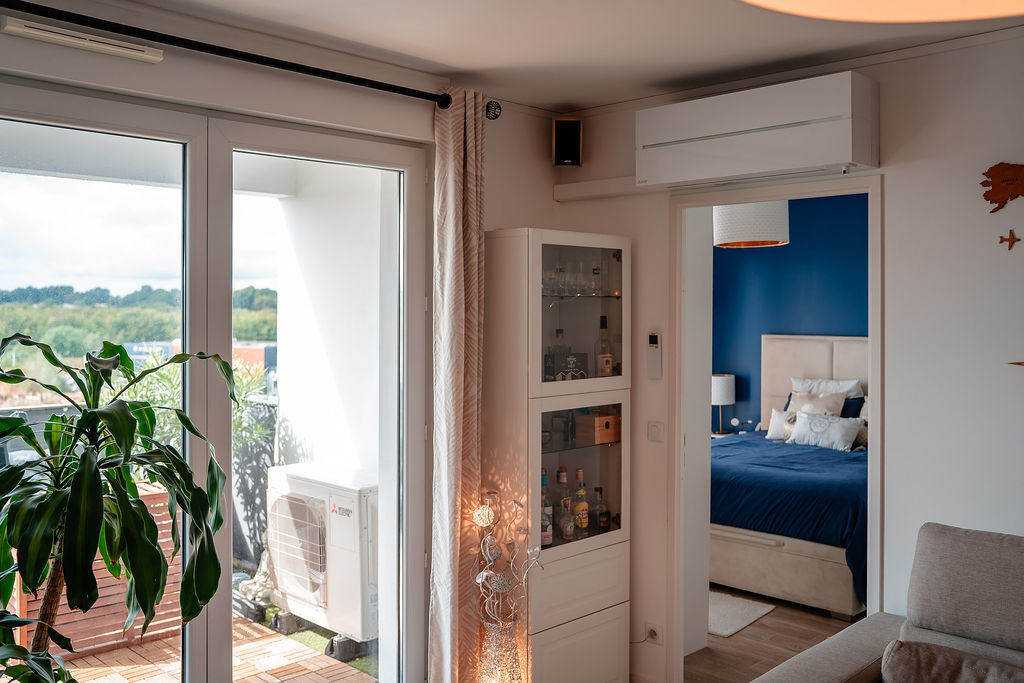 Pompe à chaleur air-air sur un balcon et climatisation murale dans un salon