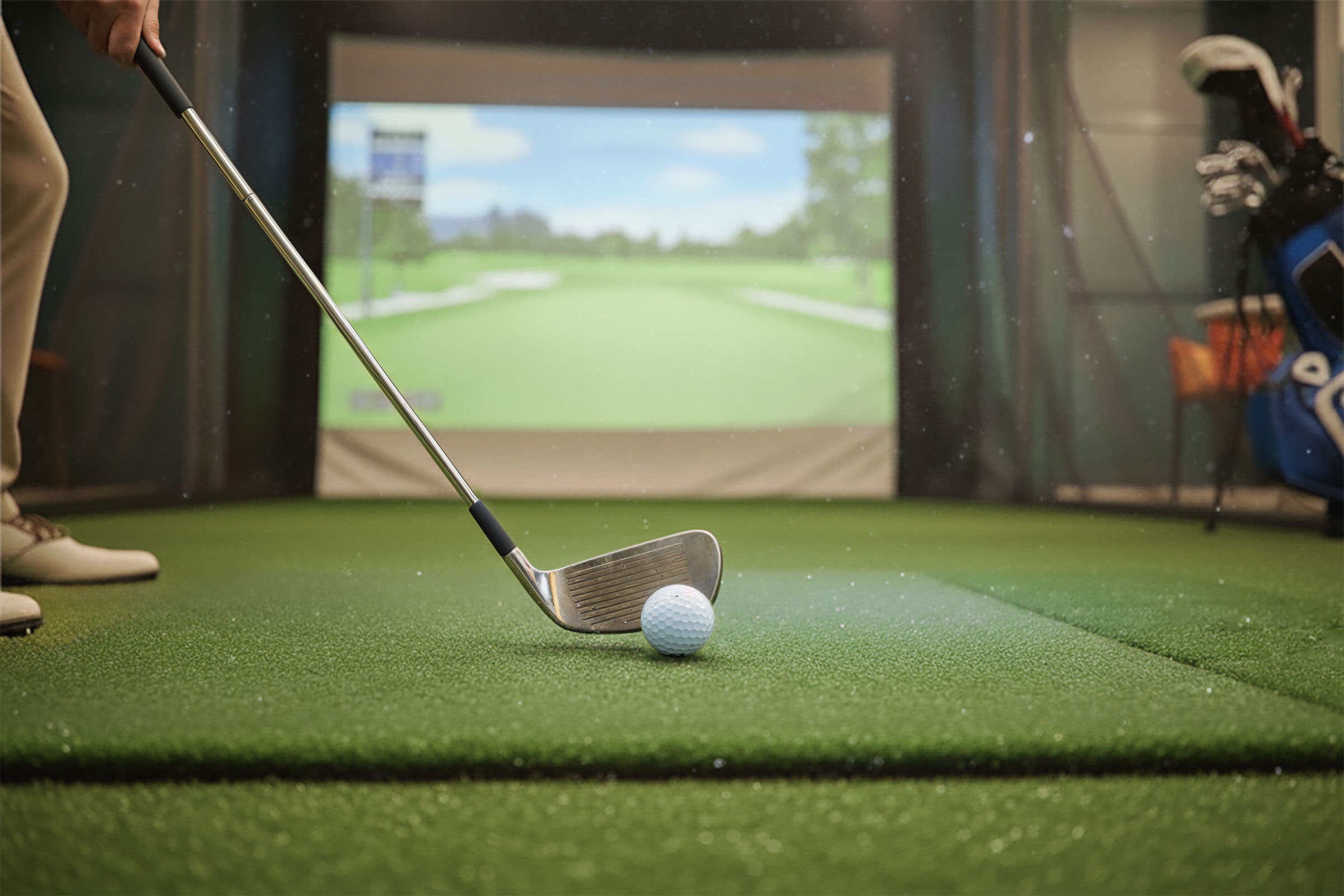 Golf simulator amenity with a putting mat and player preparing a shot.