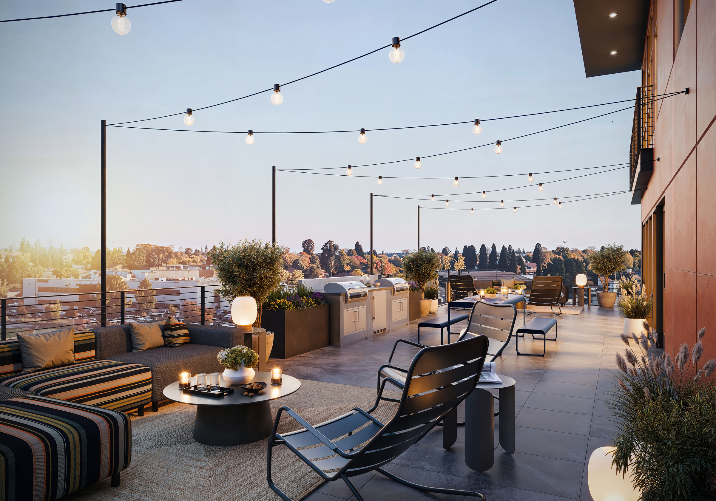 Rooftop lounge with string lights, outdoor seating, and a fire pit at sunset