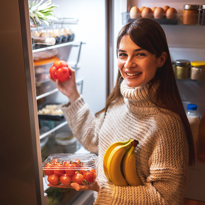 Woman smiling while stocking a refrigerator with fresh groceries delivered by Orderly in Ocean City, NJ