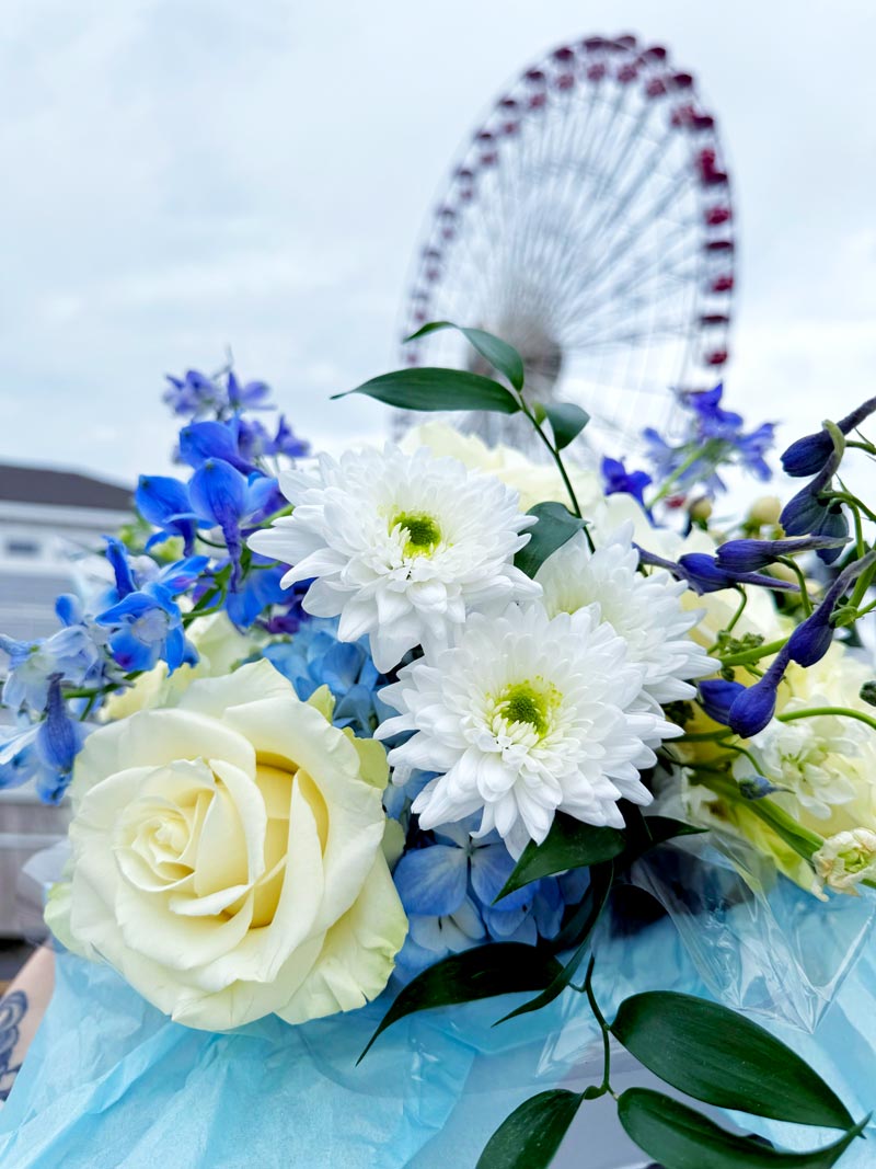 Blue and white floral bouquet delivered by Orderly Services in Ocean City, NJ with ferris wheel in the background