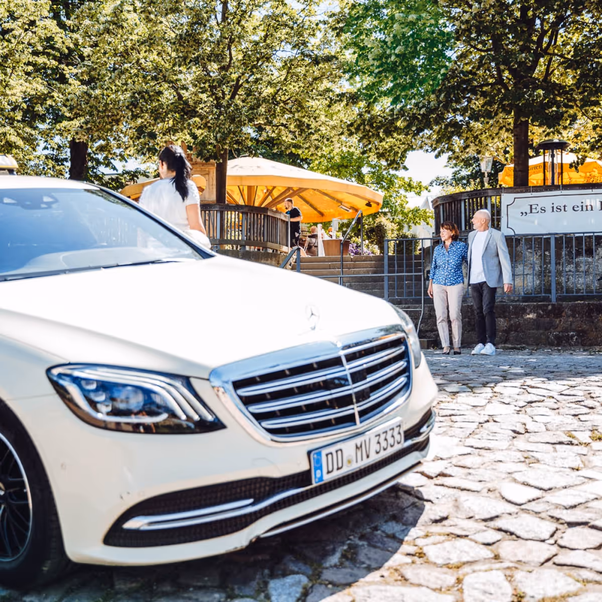 Ein Paar läuft auf eine Treppe zu, während im Vordergrund ein Taxi steht.
