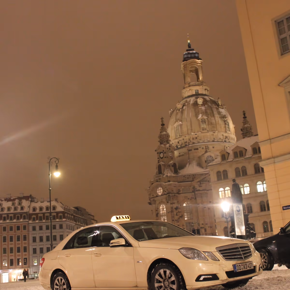 Ein Taxi vor der Frauenkirche in Dresden, aufgenommen bei Nacht.
