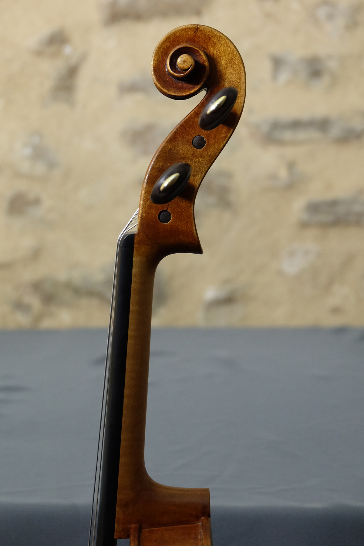 Deux têtes de violons Gagliano, original et copie, de côte sur mur en pierre