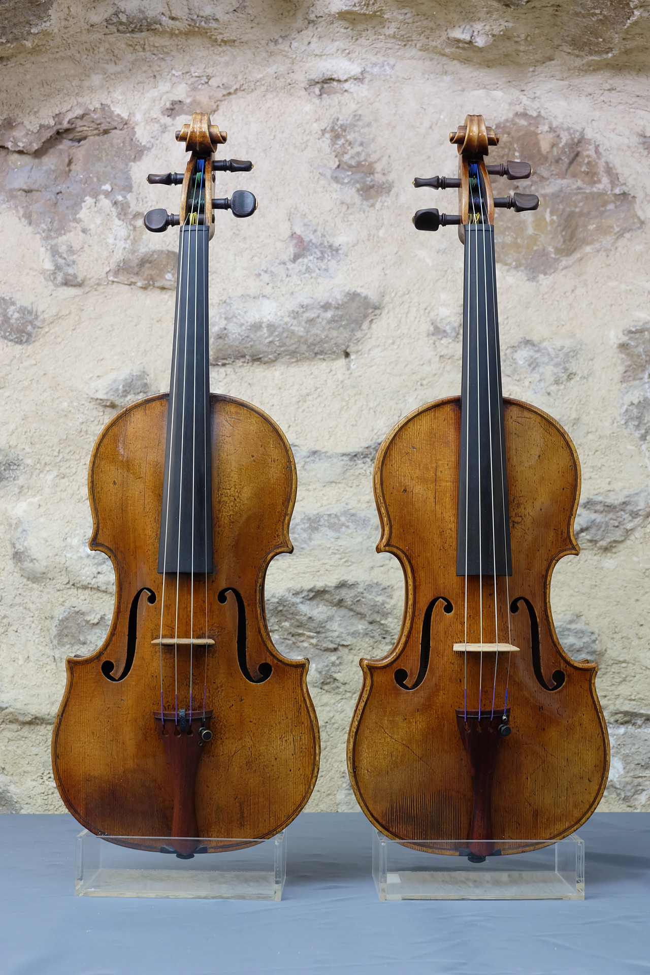 Deux violons Gagliano, original et copie, de face en détails sur mur en pierre