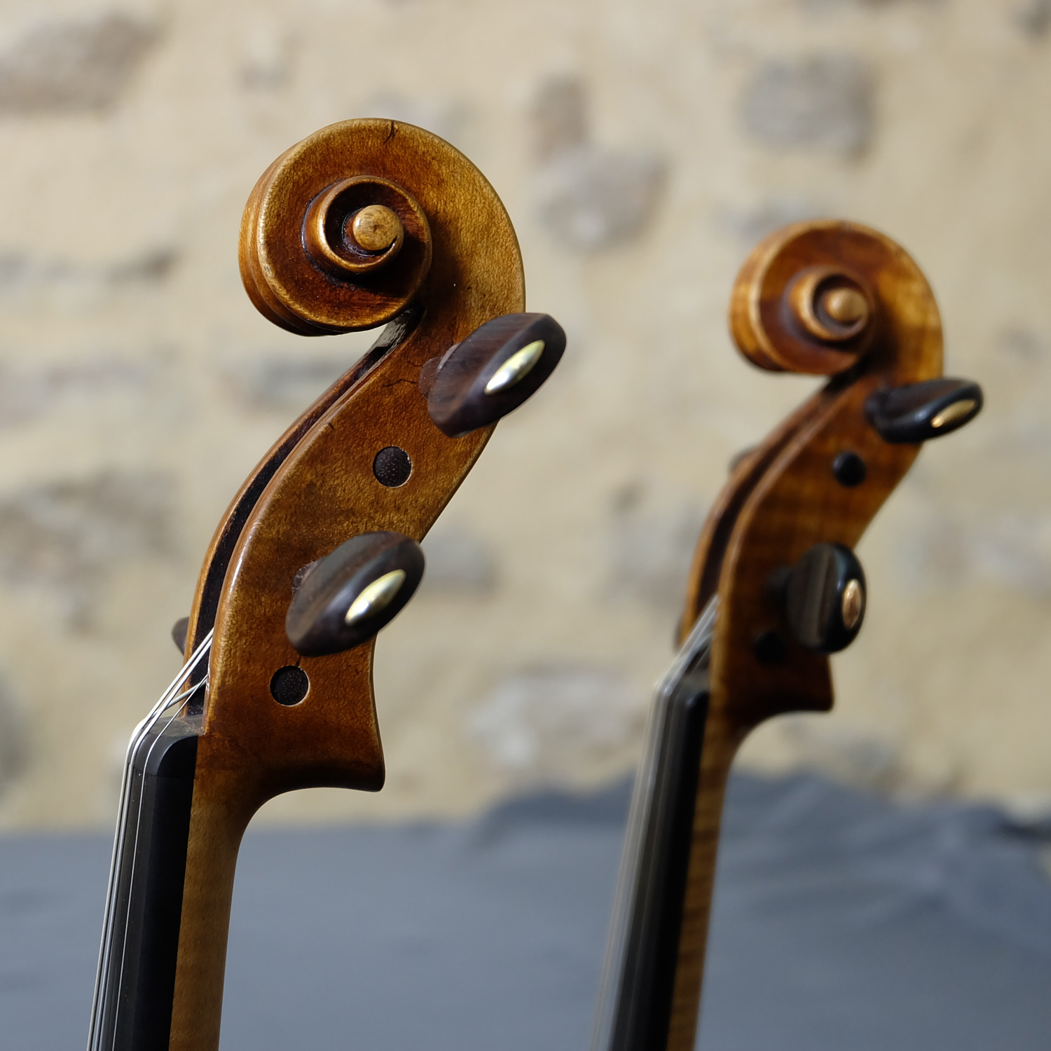Deux têtes de violons Gagliano, original et copie, de côte sur mur en pierre