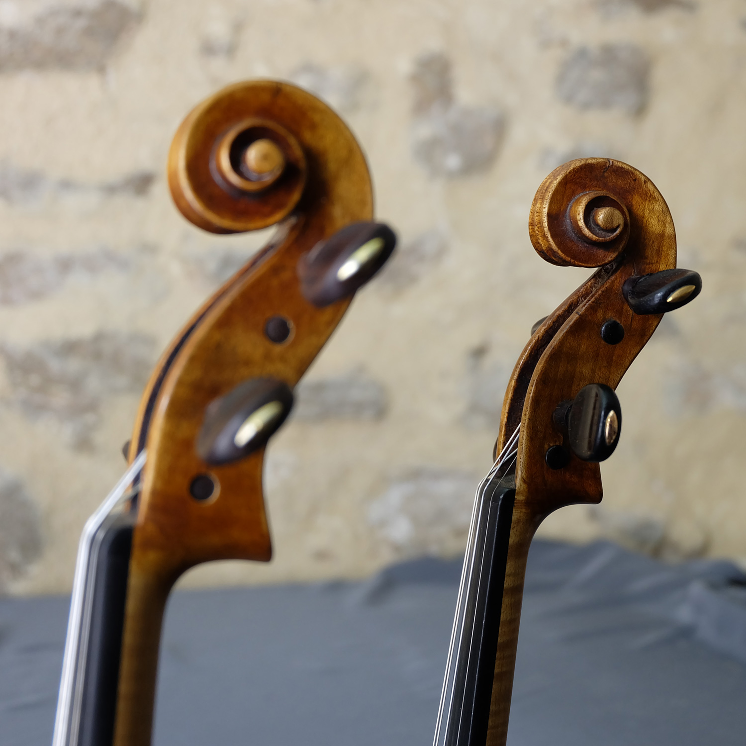 Deux têtes de violons Gagliano, original et copie, de côte sur mur en pierre