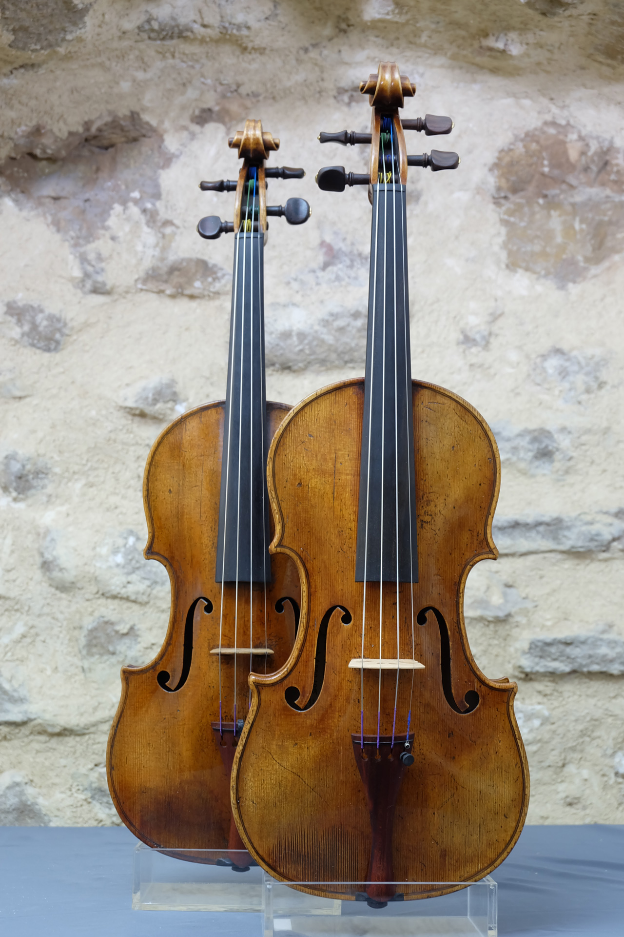Deux violons Gagliano, original et copie, de face en détails sur mur en pierre