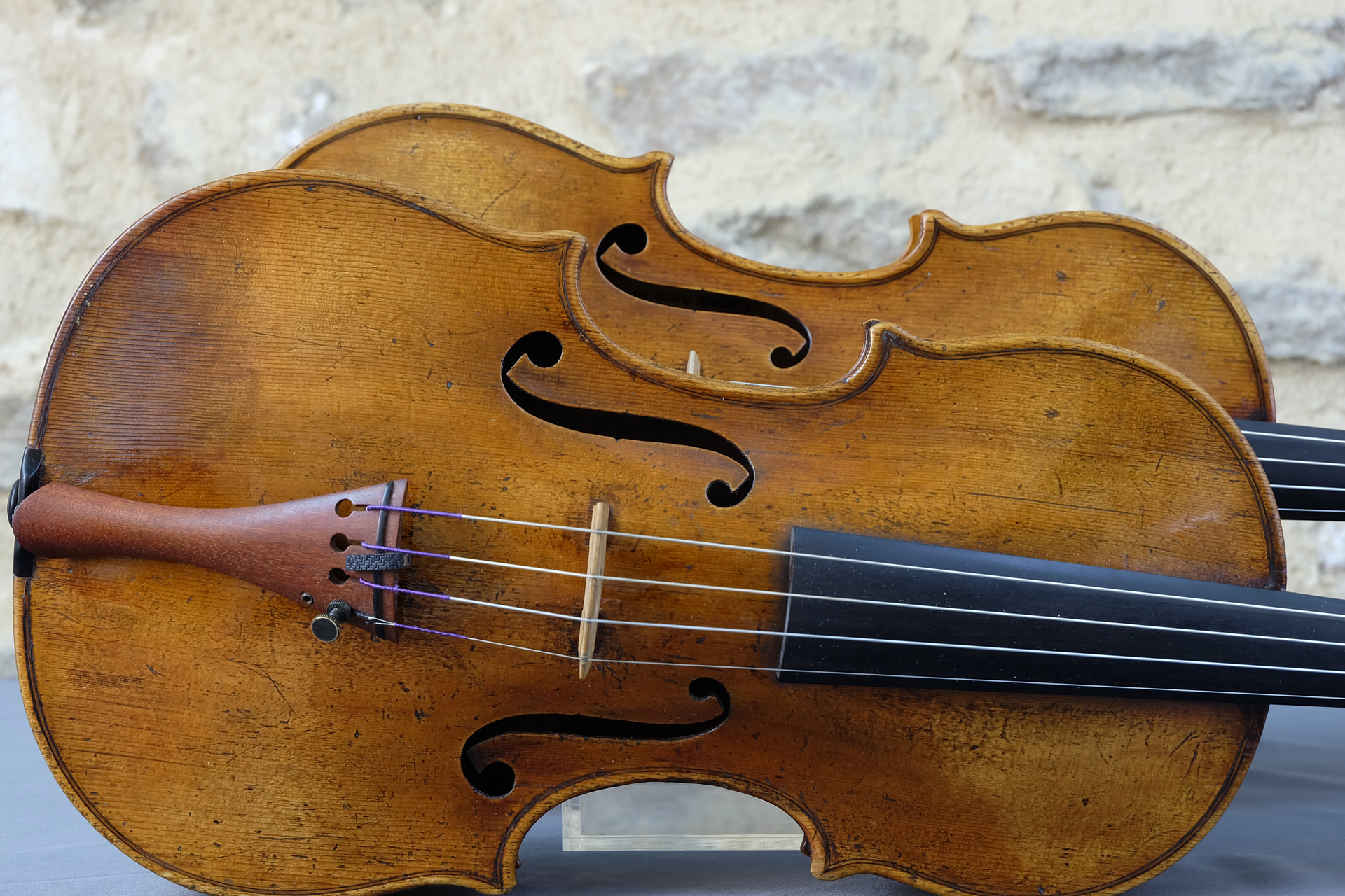 Deux violons Gagliano, original et copie, de face en détails sur mur en pierre