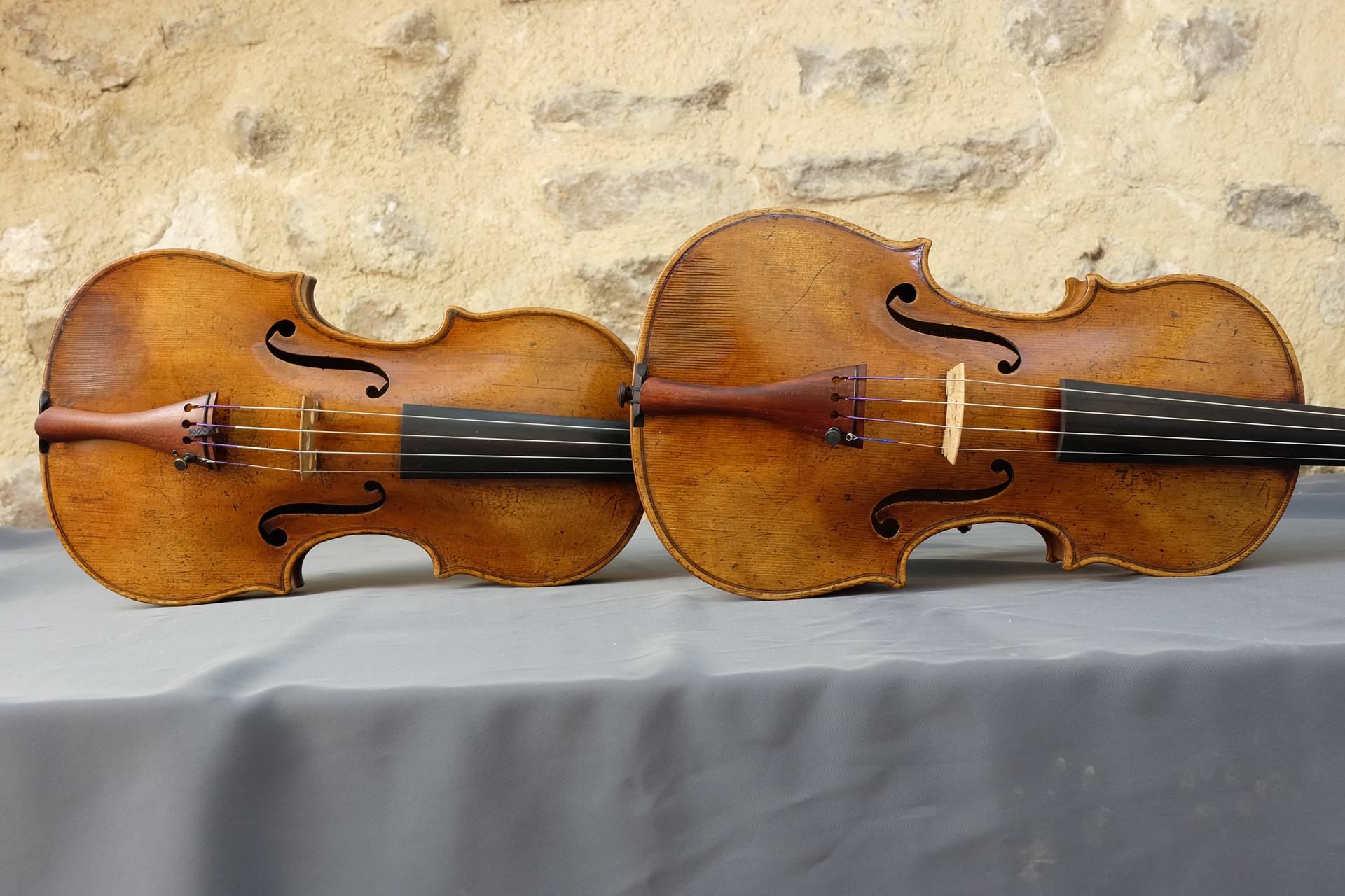 Deux violons Gagliano, original et copie, de face en détails sur mur en pierre
